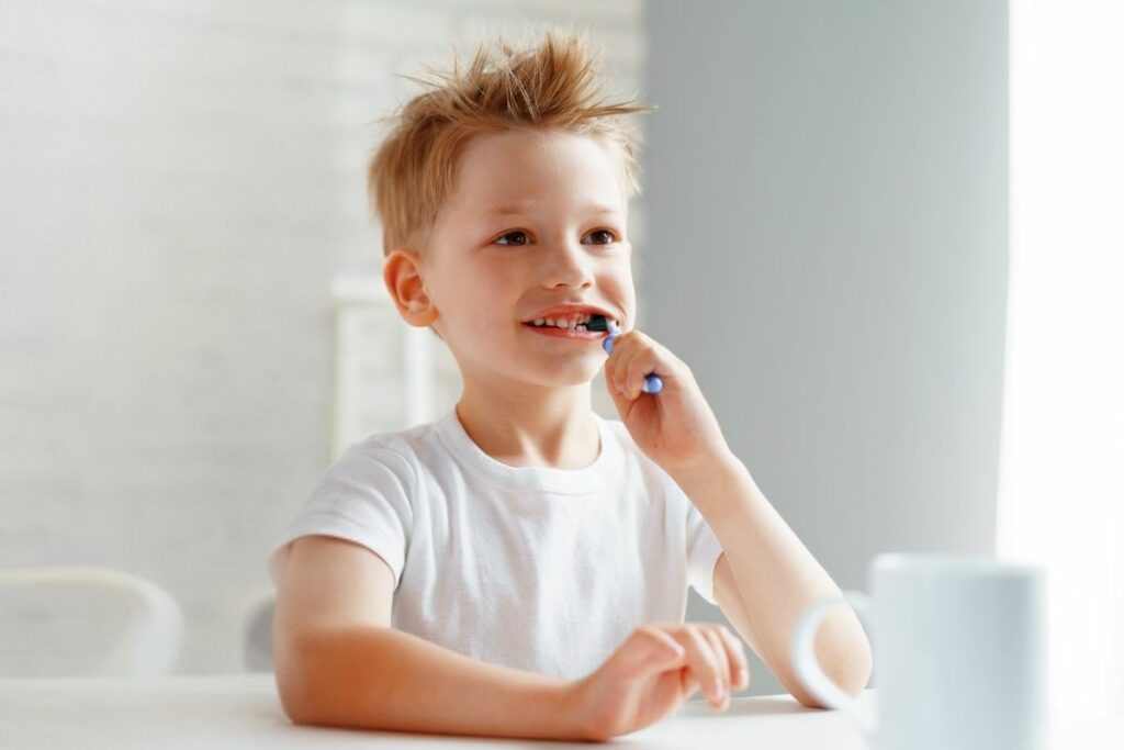 little boy brushing teeth happily