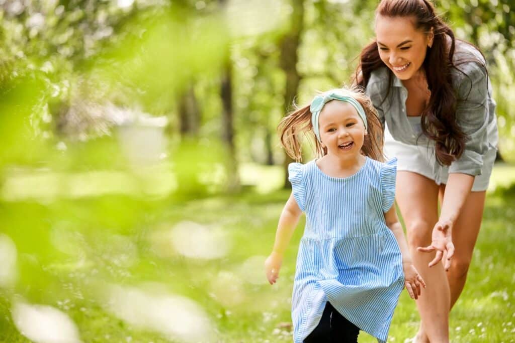 mother chasing daughter outdoors laughing