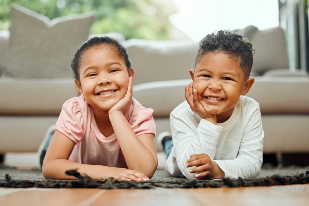 little children smiling happily laying on their bellies