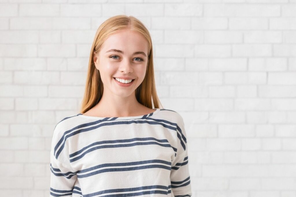 blonde teenage girl smiling happily wearing stripes